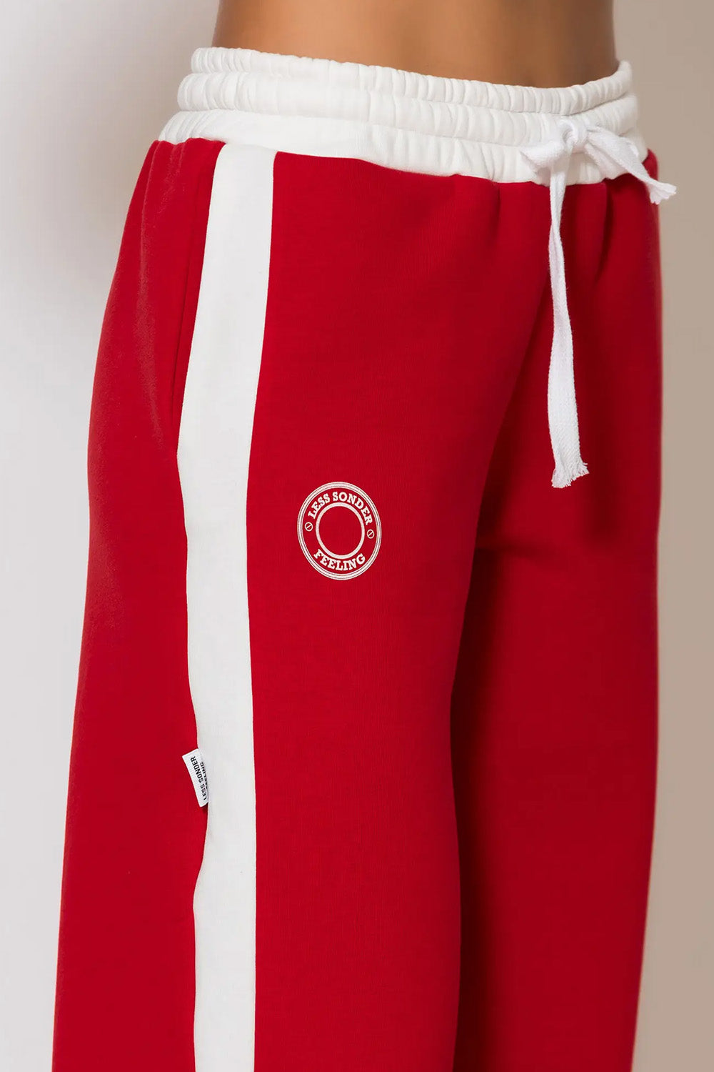 Κόκκινο φούτερ παντελόνι με λευκή ρίγα και τύπωμα logo “LESS SONDER FEELING”
