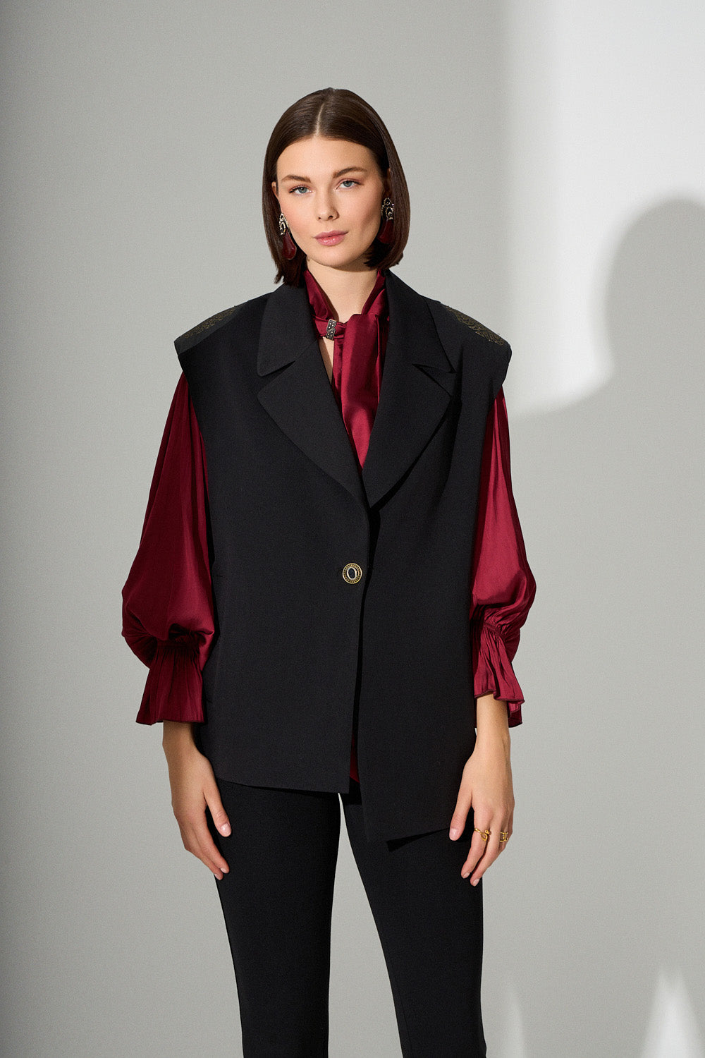 Μοντέλο με μαύρο γιλέκο με διακοσμητικούς ώμους και μπορντό πουκάμισο