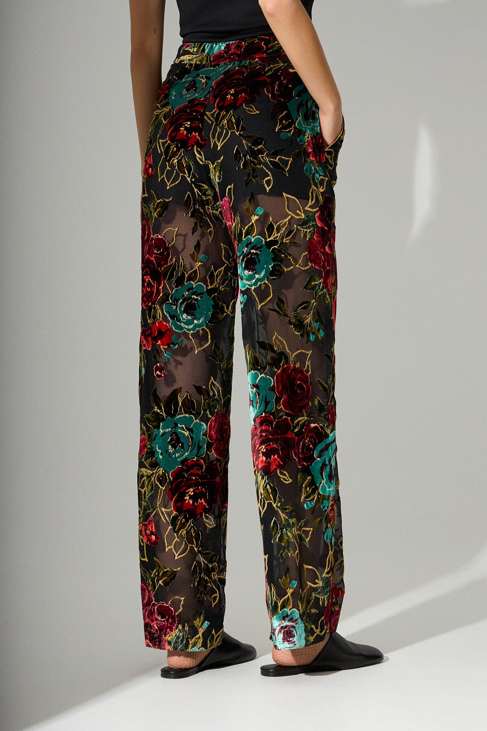 Μαύρη παντελόνα με διαφάνεια και βελούδινα λουλούδια σε κόκκινο και πράσινο με χρυσές λεπτομέρειες.