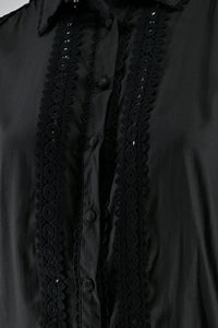 Close-up of a black shirt featuring lace details along the button placket and collar.