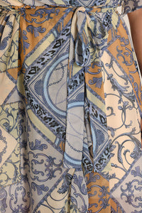 Close-up of a belted muslin dress featuring intricate blue and gold patterns, ideal for boho-chic looks.