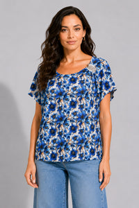 Εμπριμέ μπλούζα με μπλε floral print, κοντό μανίκι, στρογγυλή λαιμόκοψη και διακοσμητική καρφίτσα στον ώμο.
