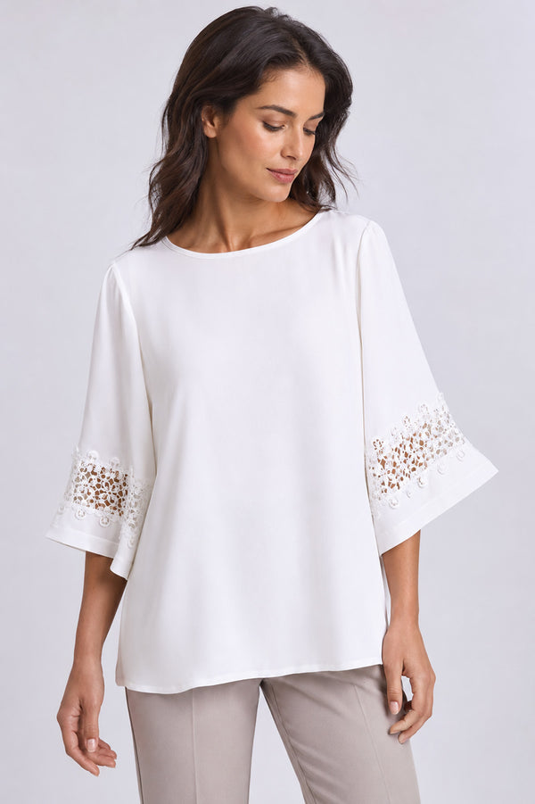 Γυναικεία off white μπλούζα με στρογγυλή λαιμόκοψη και δαντελένια λεπτομέρεια στα μανίκια.