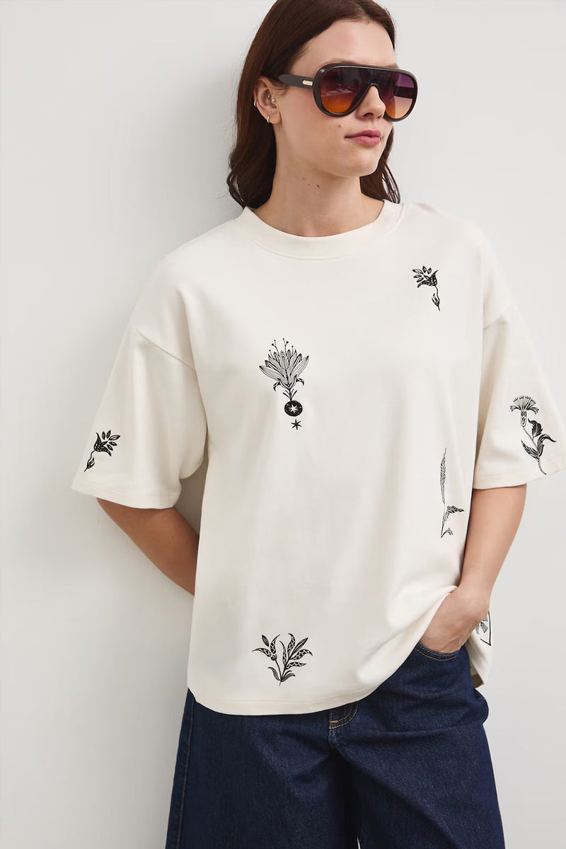 Oversize εκρού βαμβακερό t-shirt με minimal print σε μαύρες λεπτομέρειες και φαρδιά κοντά μανίκια