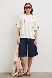 Oversize εκρού βαμβακερό t-shirt με minimal print σε μαύρες λεπτομέρειες και φαρδιά κοντά μανίκια