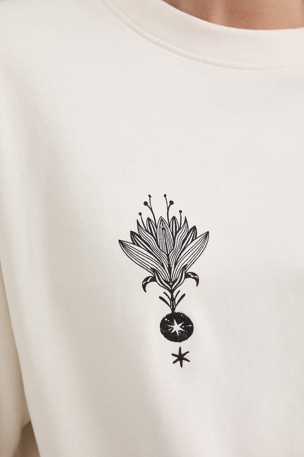 Oversize εκρού βαμβακερό t-shirt με minimal print σε μαύρες λεπτομέρειες και φαρδιά κοντά μανίκια