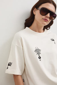 Oversize εκρού βαμβακερό t-shirt με minimal print σε μαύρες λεπτομέρειες και φαρδιά κοντά μανίκια