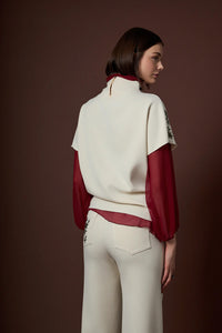 Αμάνικη εκρού γυναικεία μπλούζα με διακριτικές κεντημένες λεπτομέρειες στους ώμους, φορεμένη σε μοντέλο σε studio φωτογράφιση