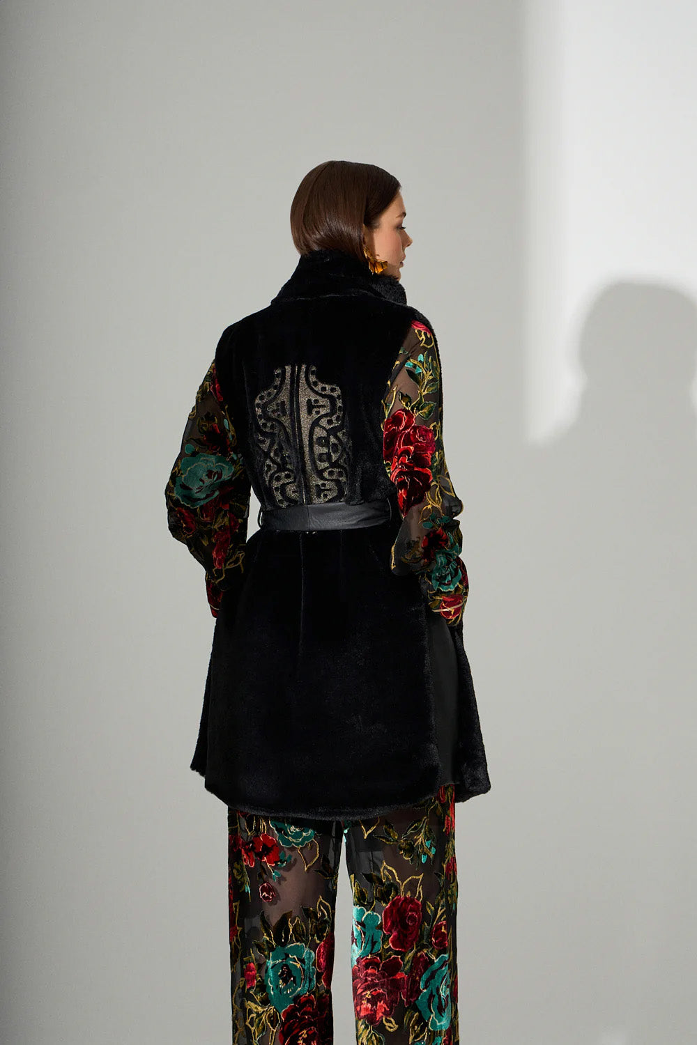 Αμάνικο μαύρο γυναικείο παλτό με ζώνη στη μέση και γιακά, φορεμένο σε μοντέλο σε studio φωτογράφιση