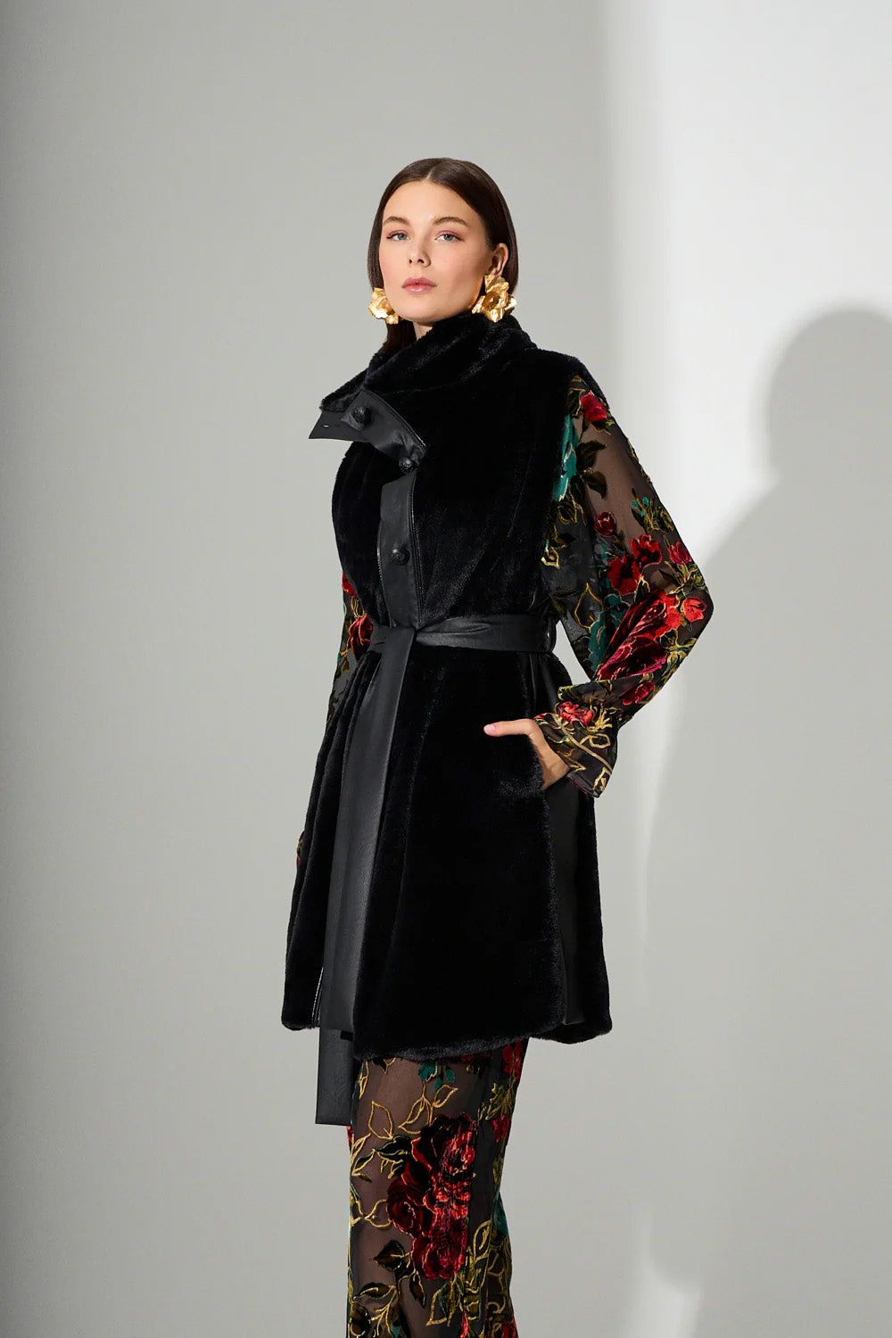 Αμάνικο μαύρο γυναικείο παλτό με ζώνη στη μέση και γιακά, φορεμένο σε μοντέλο σε studio φωτογράφιση