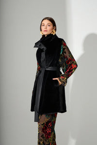 Αμάνικο μαύρο γυναικείο παλτό με ζώνη στη μέση και γιακά, φορεμένο σε μοντέλο σε studio φωτογράφιση