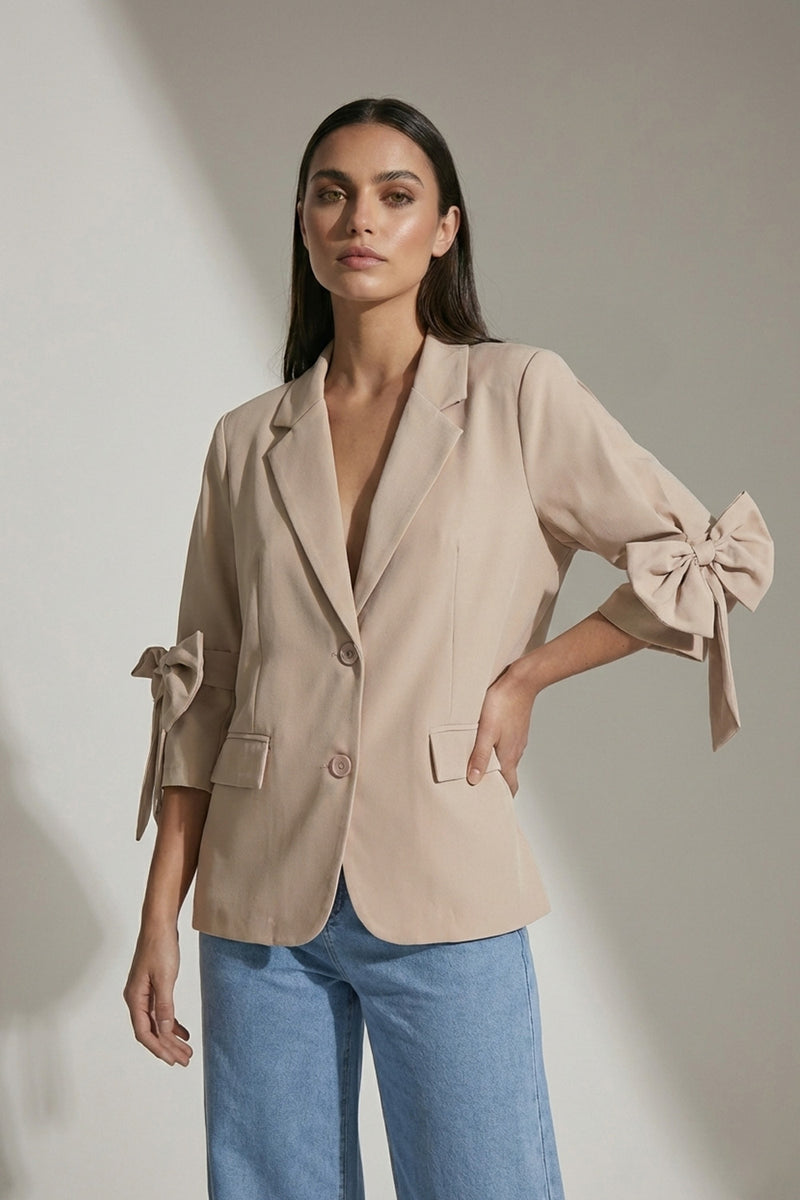 Μπεζ σακάκι με δύο κουμπιά και φιόγκους στα μανίκια 3/4, ίσια κομψή γραμμή.