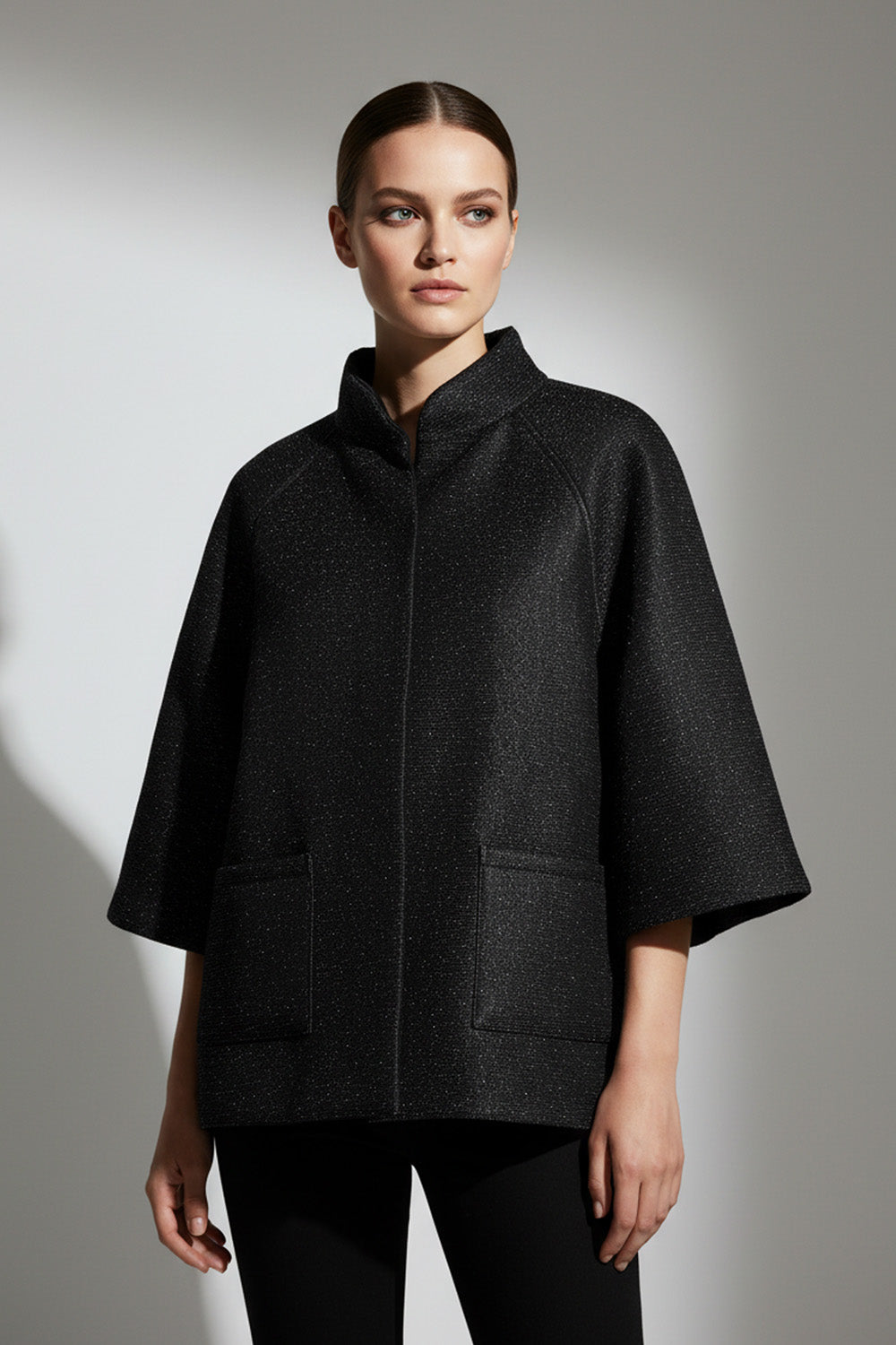 Μαύρο minimal μπουφάν με μανίκι 3/4 και όρθιο γιακά, φωτογραφημένο σε μοντέλο studio.