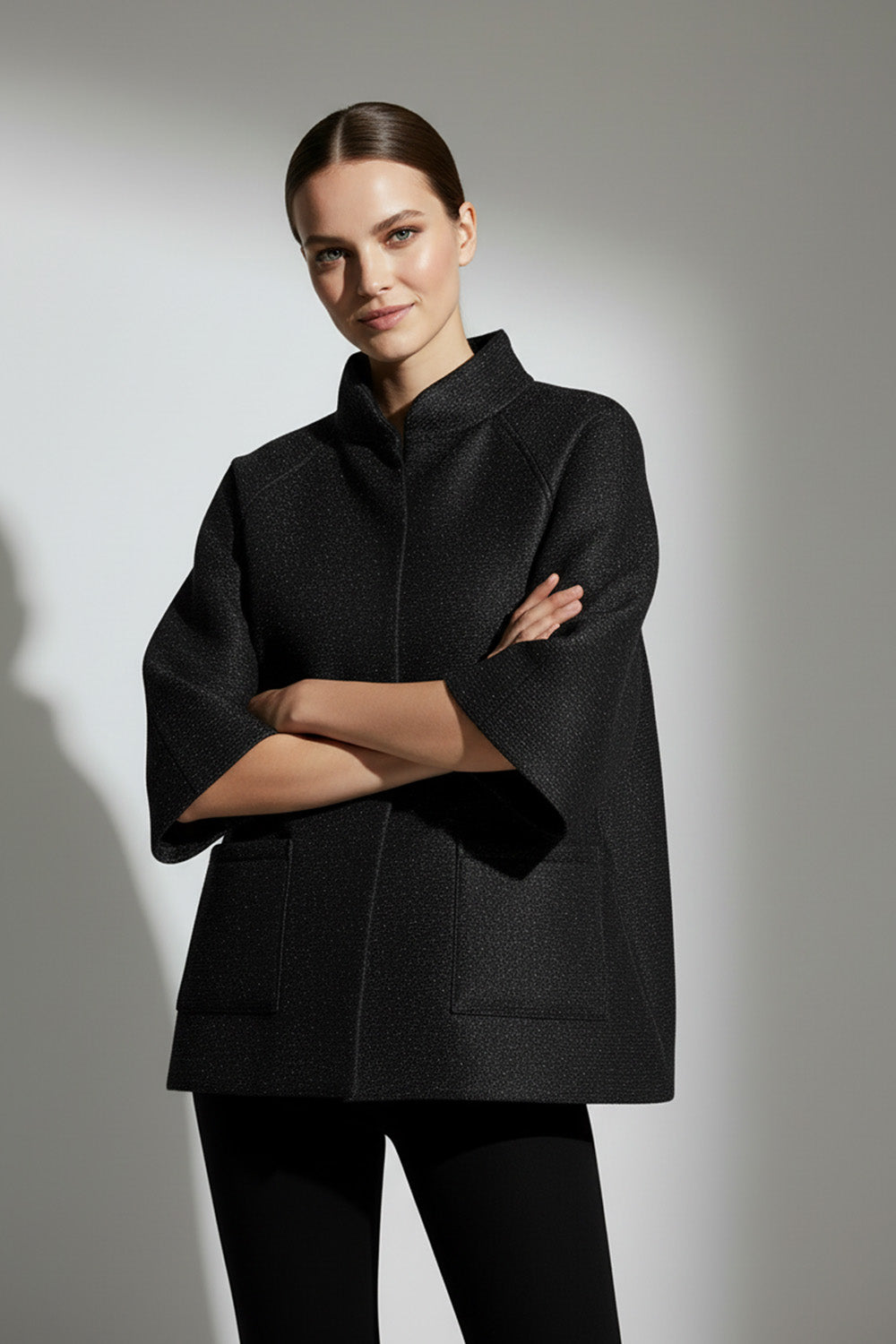 Μαύρο minimal μπουφάν με μανίκι 3/4 και όρθιο γιακά, φωτογραφημένο σε μοντέλο studio.