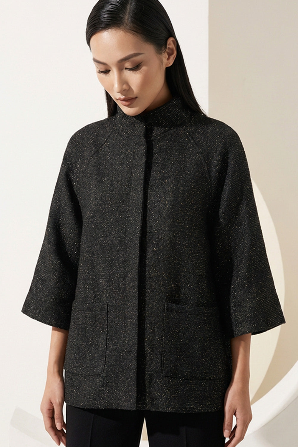 Μαύρο minimal μπουφάν με μανίκι 3/4 και όρθιο γιακά, φωτογραφημένο σε μοντέλο studio.