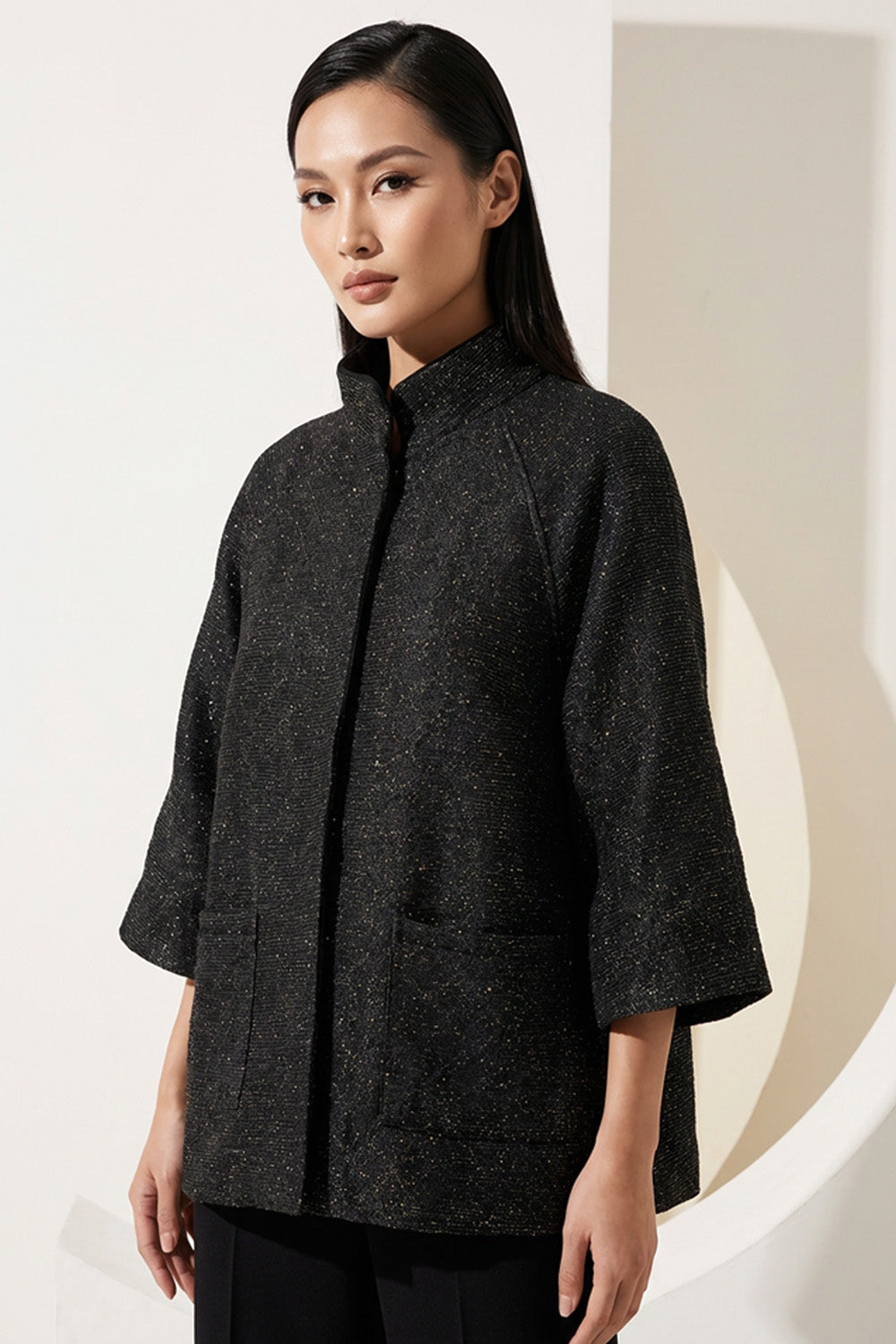 Μαύρο minimal μπουφάν με μανίκι 3/4 και όρθιο γιακά, φωτογραφημένο σε μοντέλο studio.