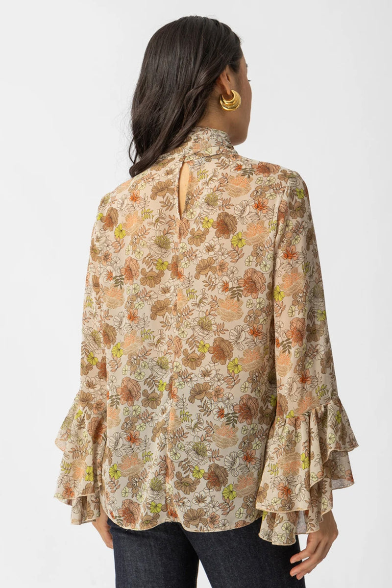 Εμπριμέ μπλούζα με διαφάνεια, φιόγκο στο λαιμό και μανίκια με βολάν σε αέρινη γραμμή.