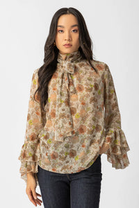 Εμπριμέ μπλούζα με διαφάνεια, φιόγκο στο λαιμό και μανίκια με βολάν σε αέρινη γραμμή.