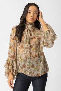 Εμπριμέ μπλούζα με διαφάνεια, φιόγκο στο λαιμό και μανίκια με βολάν σε αέρινη γραμμή.