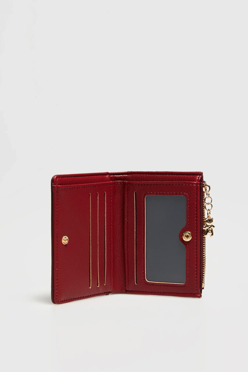 Μπορντό γυναικείο πορτοφόλι με ανάγλυφη υφή, χρυσό λογότυπο, μεταλλικό αρκουδάκι και αποσπώμενη καρτοθήκη.