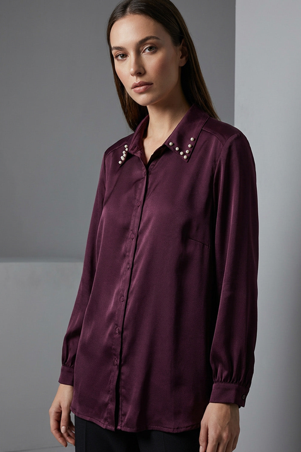 Μπορντό γυναικείο πουκάμισο με μεταλλικά τρουκς στον γιακά και μακρύ μανίκι, σε άνετη γραμμή.