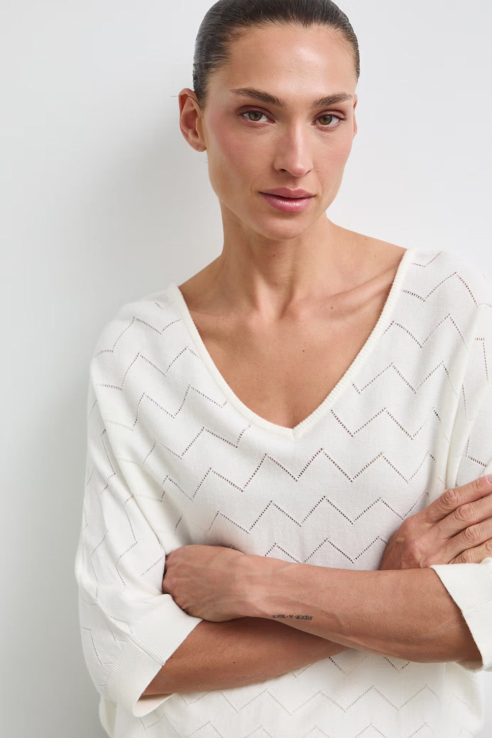 Γυναικεία πλεκτή μπλούζα off white με V λαιμόκοψη και διάτρητο γεωμετρικό σχέδιο