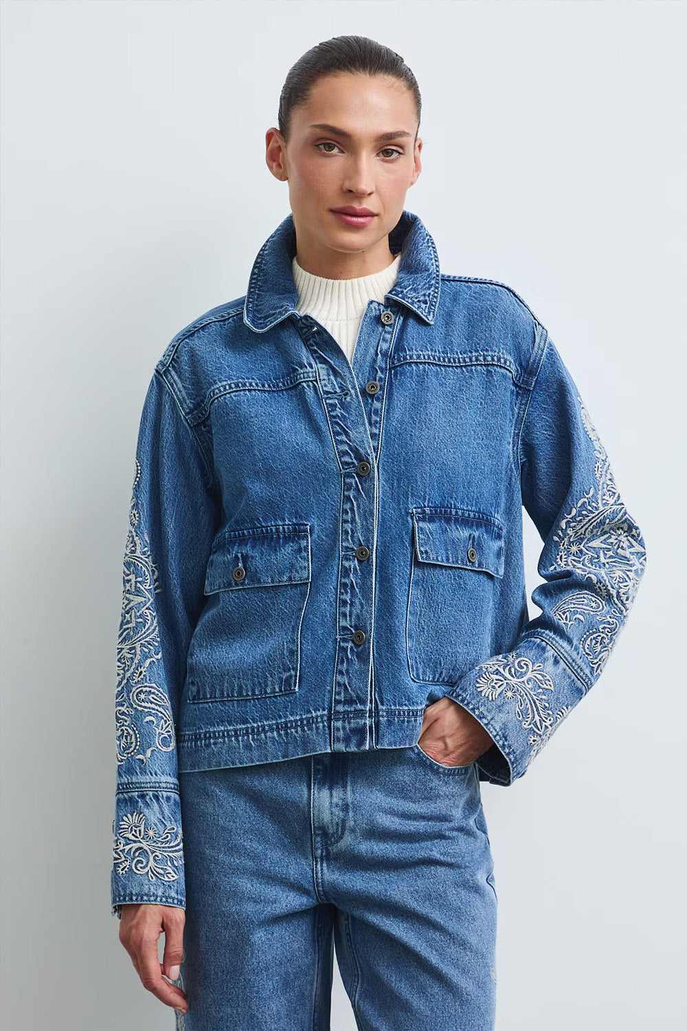 Γυναικείο μπλε denim jacket με εκρού κεντήματα στα μανίκια και μπροστινές τσέπες