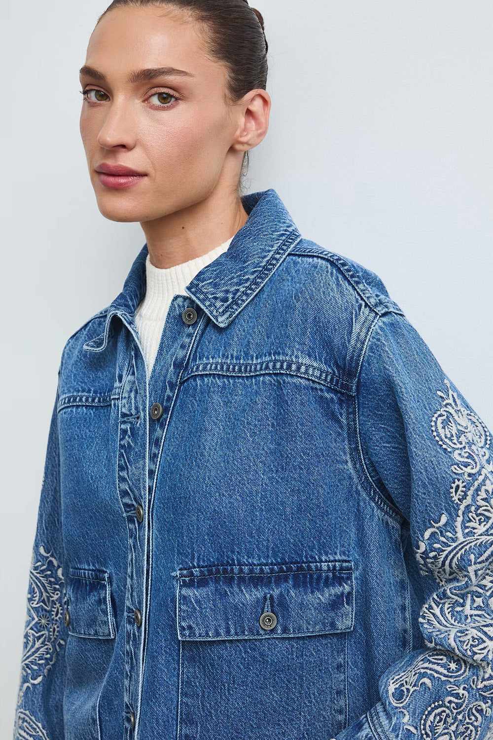 Γυναικείο μπλε denim jacket με εκρού κεντήματα στα μανίκια και μπροστινές τσέπες