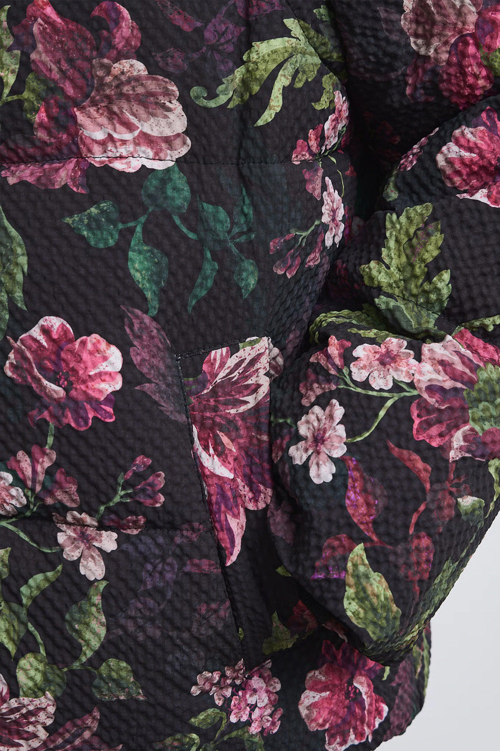 Γυναικείο καπιτονέ μπουφάν με floral σχέδια σε μπορντό, ροζ και πράσινο, ψηλό γιακά και μπροστινό φερμουάρ.