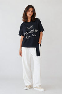 Γυναικείο μαύρο T-shirt με κεντημένο μήνυμα και διακοσμητική πλαϊνή κορδέλα στο τελείωμα.