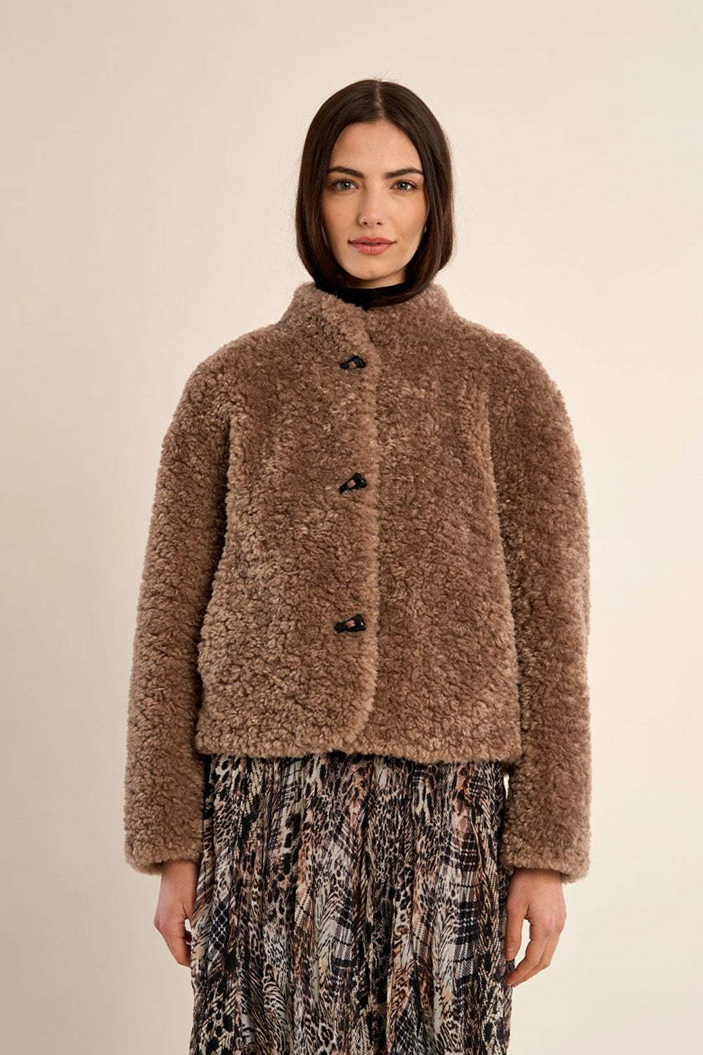 Γυναικείο κοντό teddy jacket σε καφέ απόχρωση με ψηλό γιακά, μακριά μανίκια και πλαϊνές τσέπες.