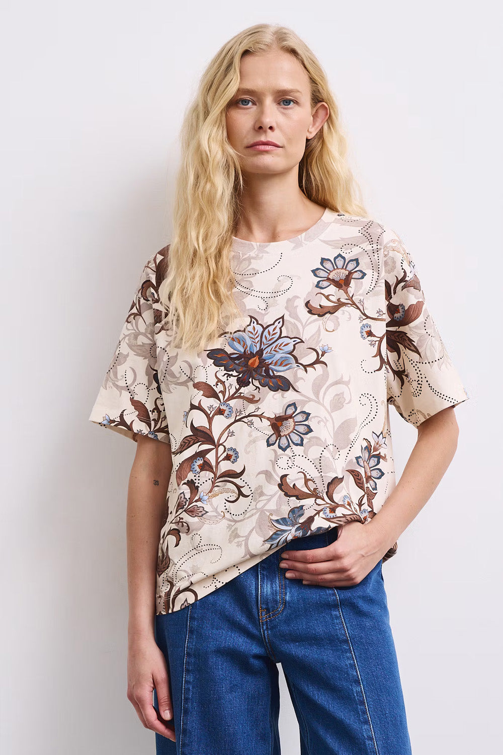 Γυναικείο εκρού T-shirt με floral print σε καφέ και γαλάζιους τόνους, άνετη γραμμή και κοντά μανίκια, πίσω όψη.