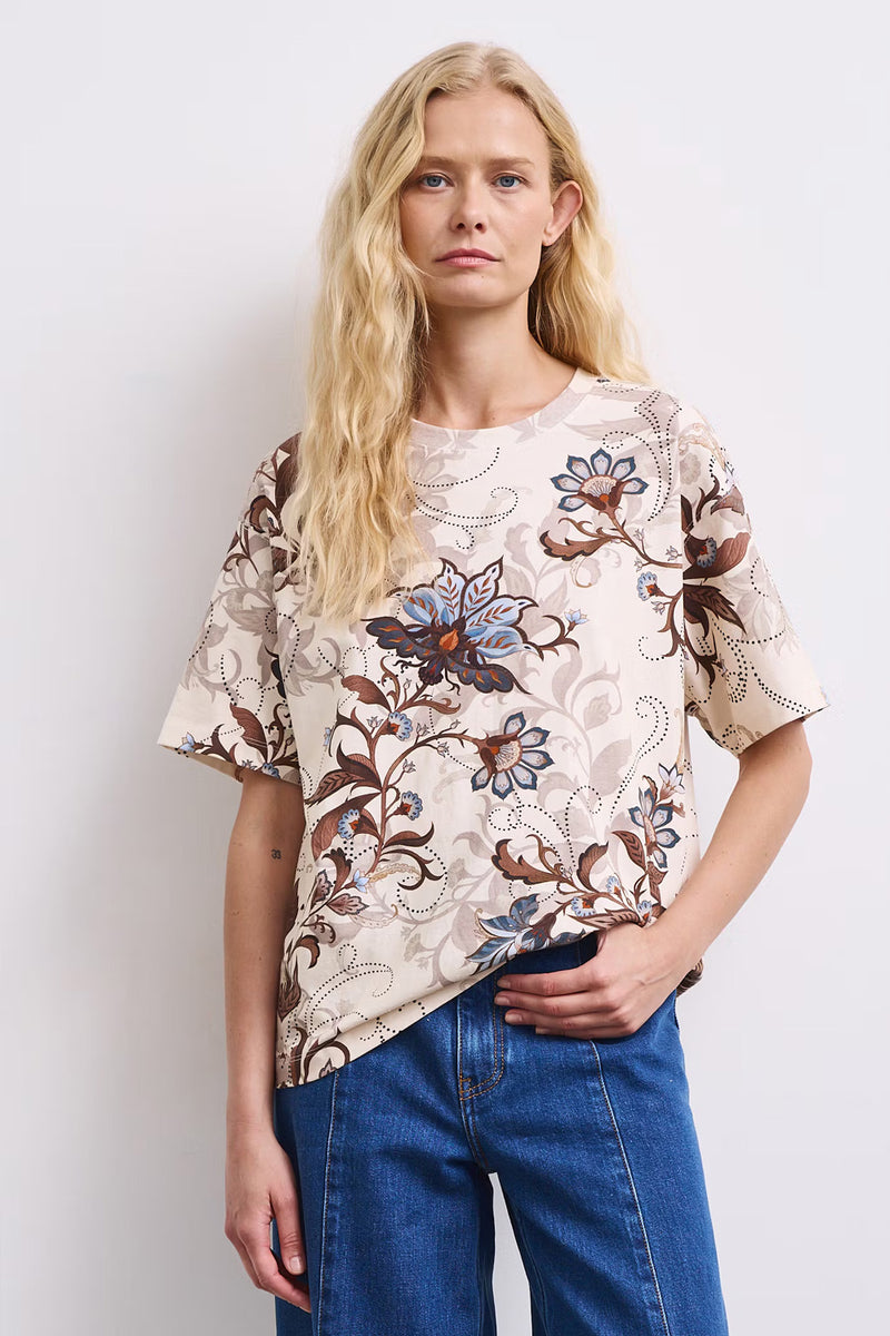 Γυναικείο εκρού T-shirt με floral print σε καφέ και γαλάζιους τόνους, άνετη γραμμή και κοντά μανίκια, πίσω όψη.