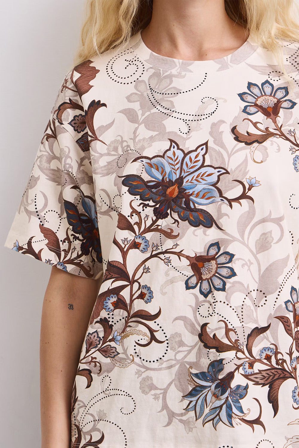 Γυναικείο εκρού T-shirt με floral print σε καφέ και γαλάζιους τόνους, άνετη γραμμή και κοντά μανίκια, πίσω όψη.
