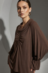 Καφέ μπλούζα ντραπέ με μακριά μανίκια και διακοσμητικό τύπωμα λιονταριού στην πλάτη, φορεμένη σε μοντέλο.