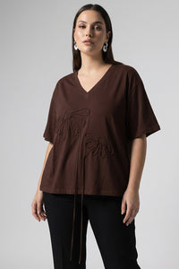 Καφέ oversized μπλούζα με V λαιμόκοψη και ανάγλυφα διακοσμητικά μοτίβα μπροστά.