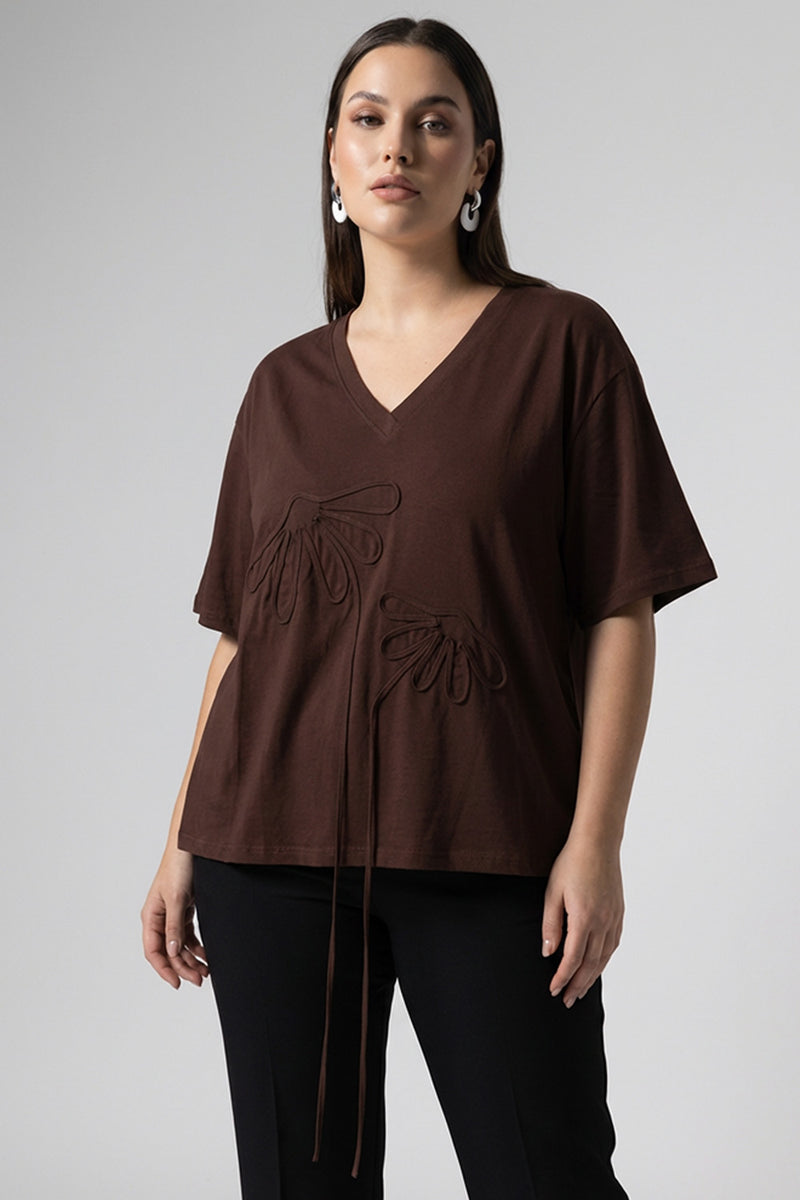 Καφέ oversized μπλούζα με V λαιμόκοψη και ανάγλυφα διακοσμητικά μοτίβα μπροστά.