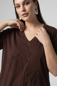 Καφέ oversized μπλούζα με V λαιμόκοψη και ανάγλυφα διακοσμητικά μοτίβα μπροστά.