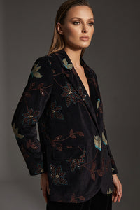 Γυναικείο κοτλέ σακάκι σε σκούρο χρώμα με floral λεπτομέρειες, σε κομψή γραμμή, φορεμένο από μοντέλο σε studio φωτογράφιση.