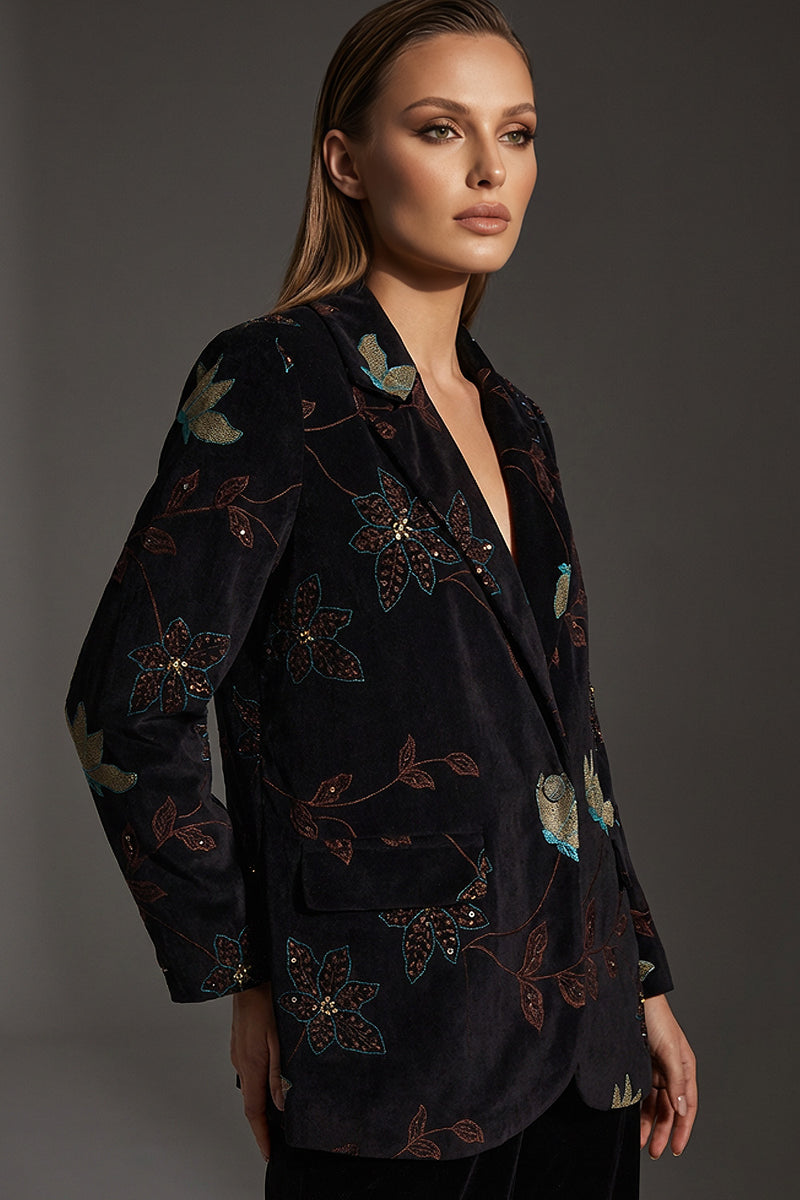 Γυναικείο κοτλέ σακάκι σε σκούρο χρώμα με floral λεπτομέρειες, σε κομψή γραμμή, φορεμένο από μοντέλο σε studio φωτογράφιση.