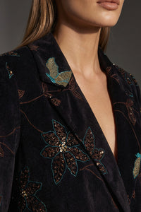 Γυναικείο κοτλέ σακάκι σε σκούρο χρώμα με floral λεπτομέρειες, σε κομψή γραμμή, φορεμένο από μοντέλο σε studio φωτογράφιση.