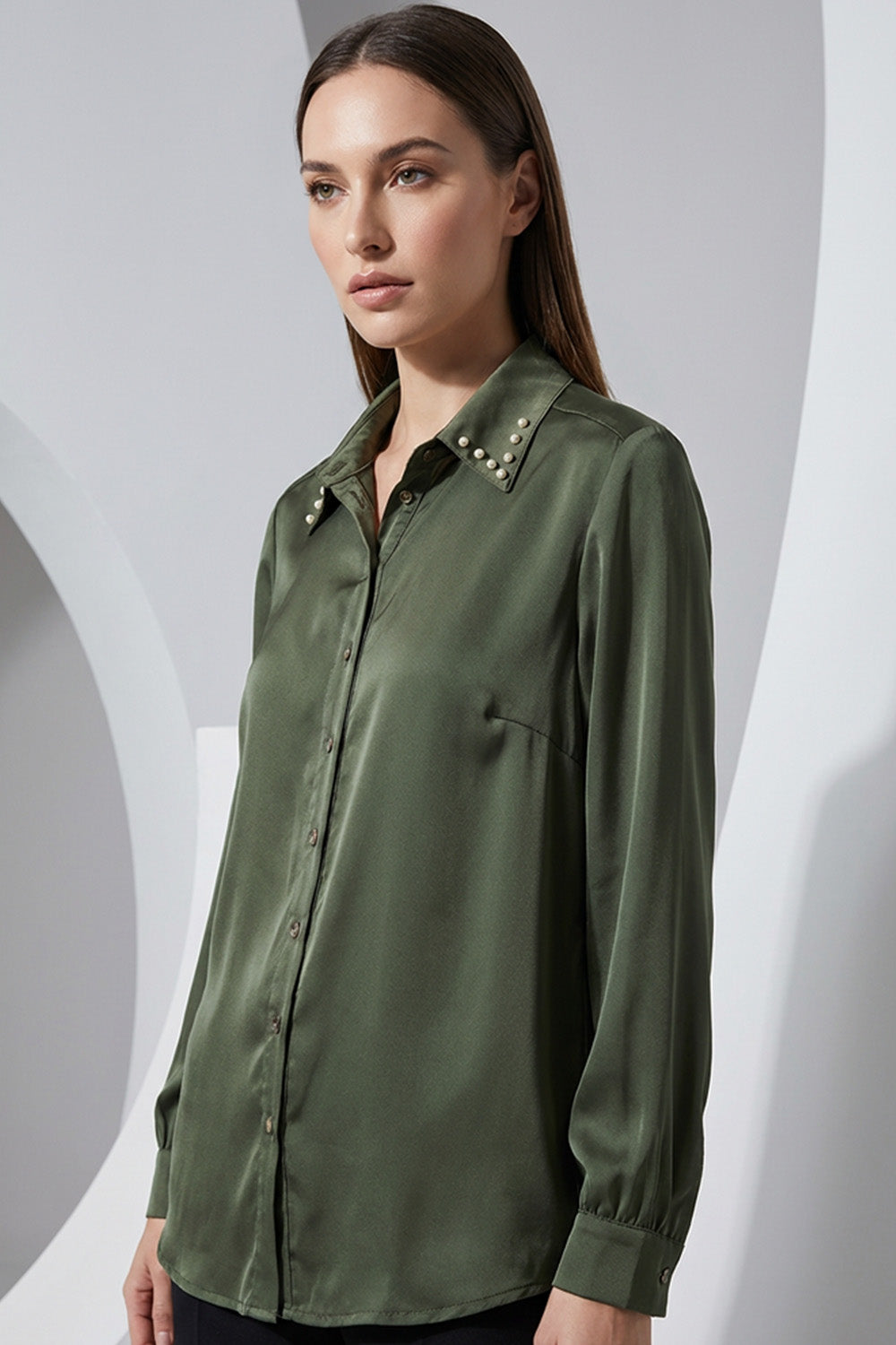 Λαδί γυναικείο πουκάμισο με μεταλλικά τρουκς στον γιακά και μακρύ μανίκι, σε άνετη γραμμή.