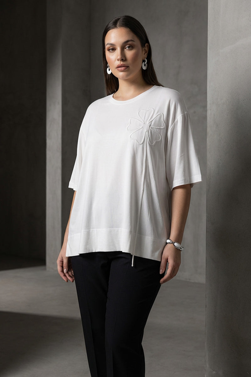 Λευκή oversized μπλούζα με ανάγλυφο λουλουδάτο σχέδιο στο στήθος και κοντά μανίκια.