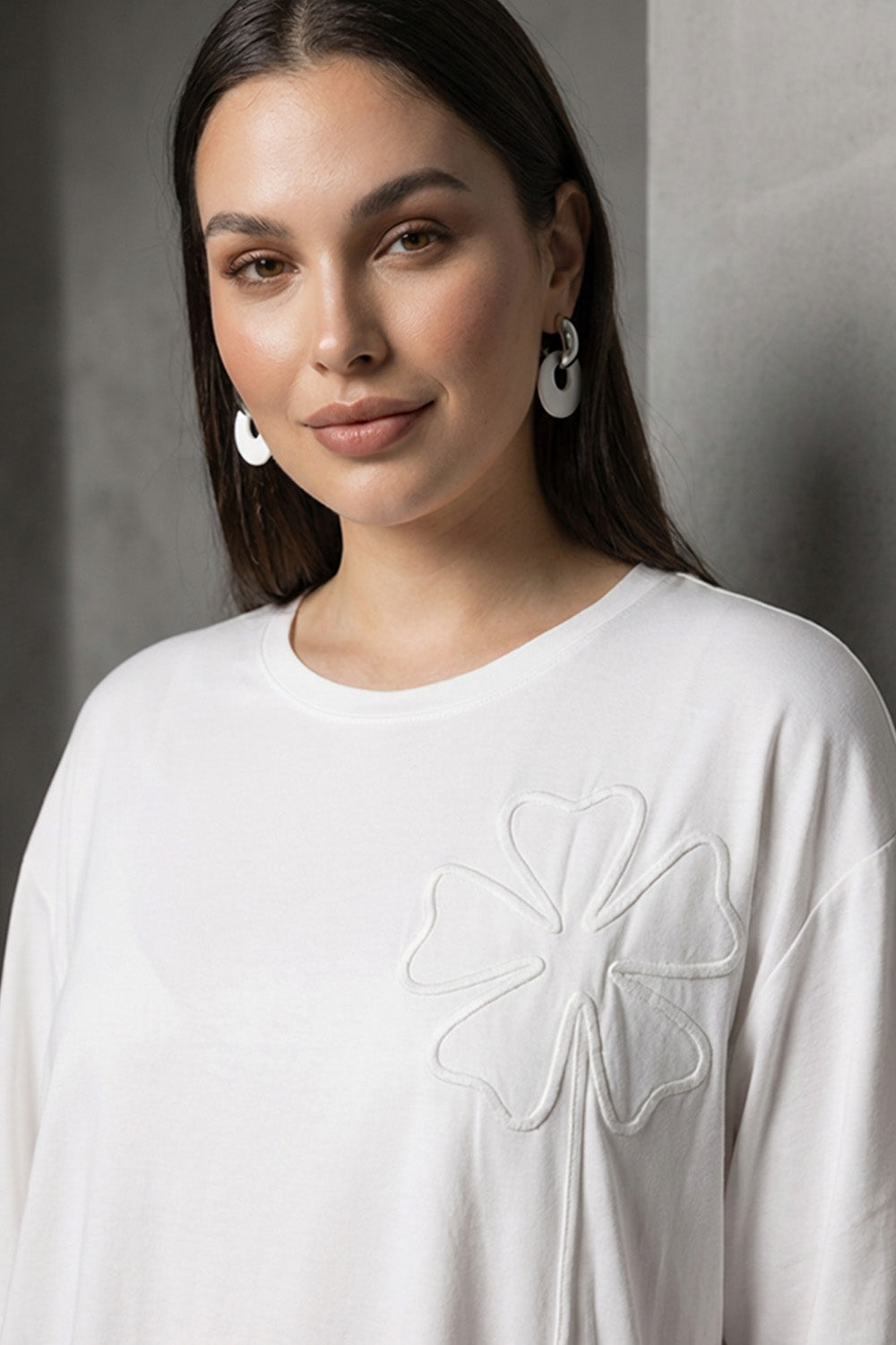 Λευκή oversized μπλούζα με ανάγλυφο λουλουδάτο σχέδιο στο στήθος και κοντά μανίκια.