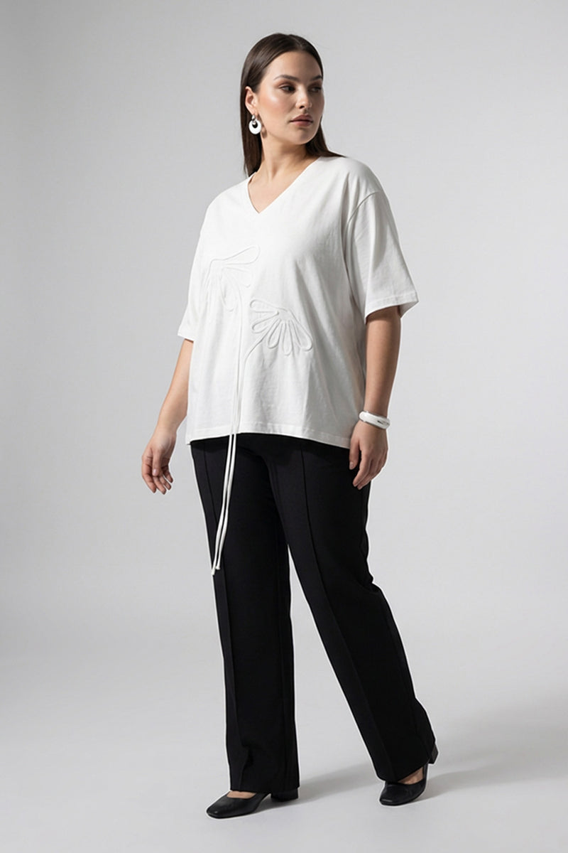 Λευκή oversized μπλούζα με V λαιμόκοψη και ανάγλυφα διακοσμητικά μοτίβα μπροστά.