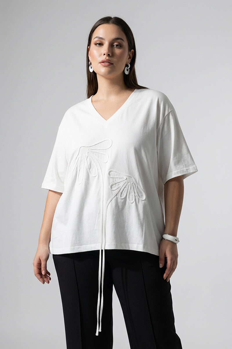 Λευκή oversized μπλούζα με V λαιμόκοψη και ανάγλυφα διακοσμητικά μοτίβα μπροστά.