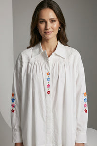 Λευκό πουκάμισο με πολύχρωμα κεντημένα λουλούδια και σφηκοφωλιά στους ώμους σε άνετη γραμμή