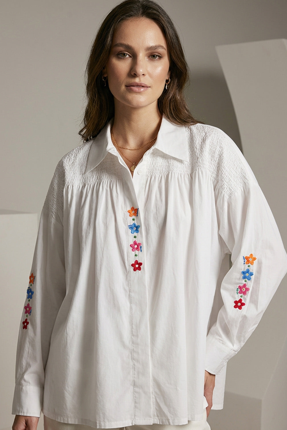 Λευκό πουκάμισο με πολύχρωμα κεντημένα λουλούδια και σφηκοφωλιά στους ώμους σε άνετη γραμμή