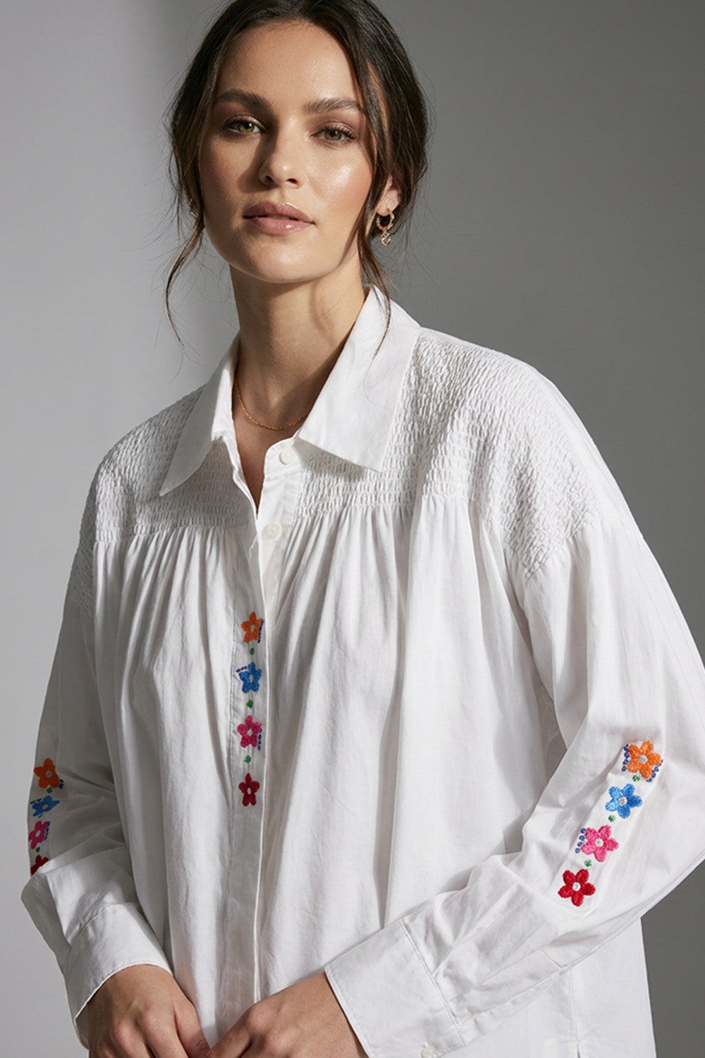 Λευκό πουκάμισο με πολύχρωμα κεντημένα λουλούδια και σφηκοφωλιά στους ώμους σε άνετη γραμμή
