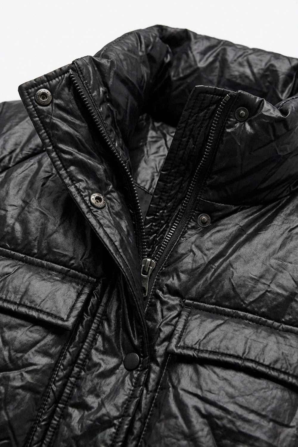 Μαύρο μπουφάν με ελαφρώς γυαλιστερή υφή, όρθιο γιακά και ζώνη στη μέση, φορεμένο από μοντέλο.